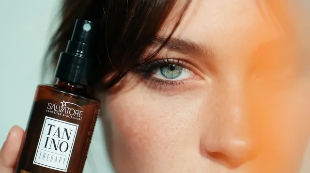 Mulher com a franja solta segurando o produto Tanino Therapy da HD Cosméticos perto do rosto